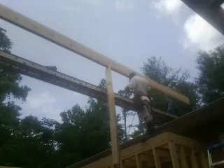 Carpenter setting a ridge beam over a new addition frame — Ice Dam Removal by Roofing Brothers in Westlake